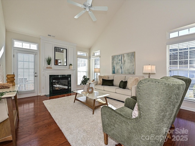 living room with a premium fireplace, dark wood-type flooring, ceiling fan, and high vaulted ceiling