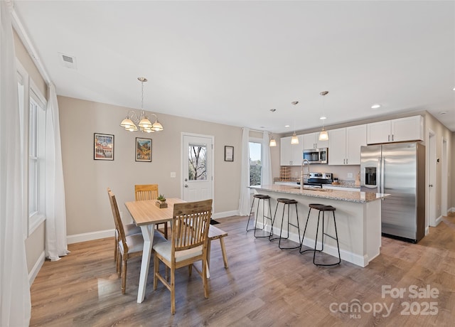 dining room featuring an inviting chandelier, sink, and light hardwood / wood-style flooring