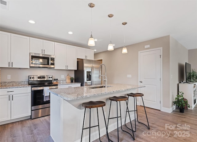 kitchen featuring sink, decorative light fixtures, a center island with sink, and appliances with stainless steel finishes