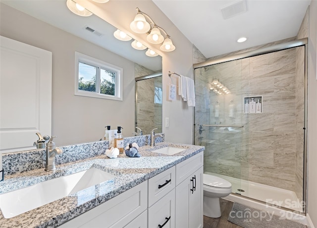 bathroom with hardwood / wood-style flooring, vanity, toilet, and a shower with shower door