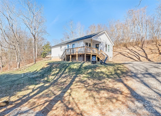 back of property with a deck and a lawn