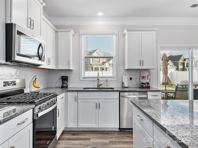 kitchen with stainless steel appliances, a sink, visible vents, white cabinetry, and light stone countertops