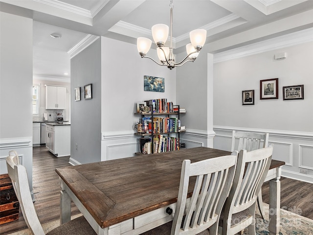 dining room featuring a decorative wall, a wainscoted wall, dark wood-style flooring, ornamental molding, and an inviting chandelier