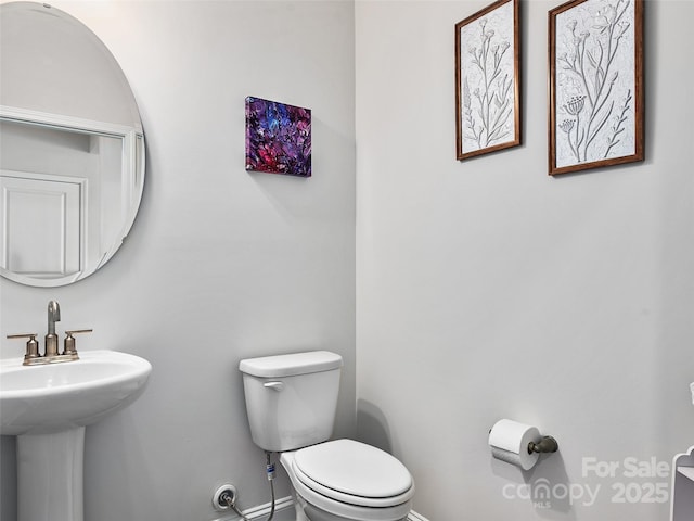 half bath with a sink, toilet, and baseboards