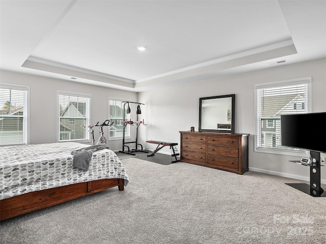 bedroom with light carpet, visible vents, multiple windows, and a tray ceiling