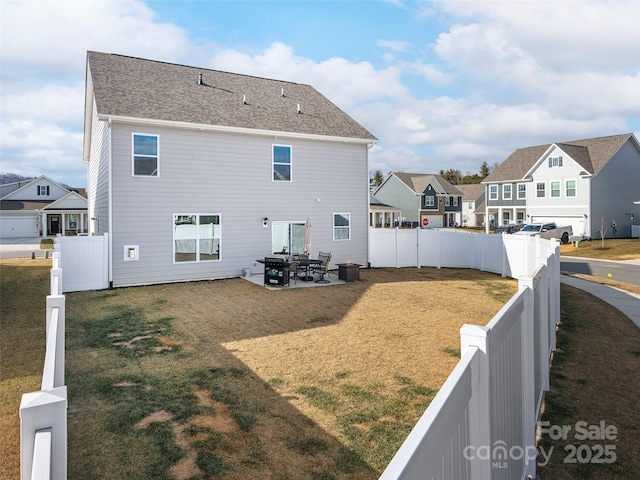 rear view of property with a fenced backyard, a residential view, a lawn, and a patio