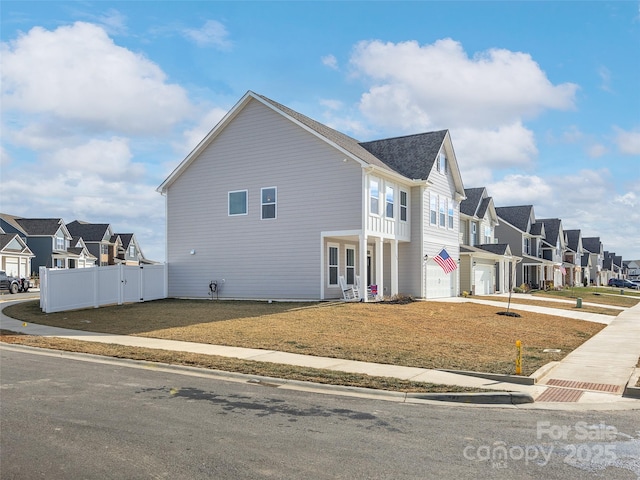 view of front of property featuring a garage, fence, driveway, a yard, and a residential view