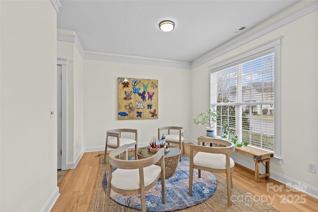 living area featuring crown molding and light hardwood / wood-style flooring