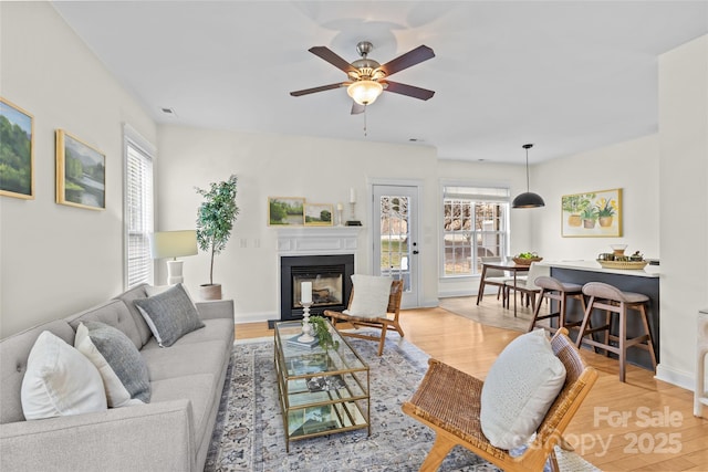 living room featuring a wealth of natural light, ceiling fan, and light wood-type flooring