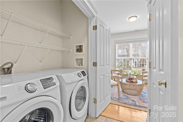 clothes washing area with separate washer and dryer and light hardwood / wood-style flooring