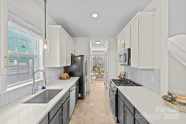 kitchen featuring sink, light tile patterned floors, appliances with stainless steel finishes, pendant lighting, and white cabinets