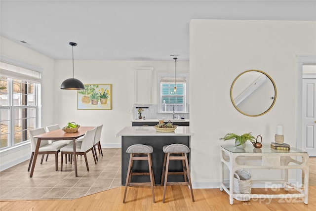 kitchen with pendant lighting, backsplash, plenty of natural light, and white cabinets