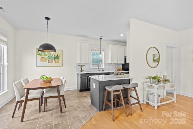 kitchen with sink, white cabinetry, tasteful backsplash, decorative light fixtures, and a kitchen breakfast bar