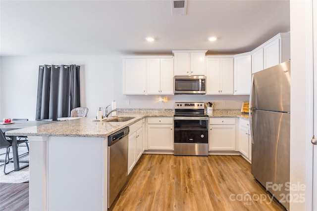 kitchen with light stone countertops, appliances with stainless steel finishes, a breakfast bar, and white cabinets