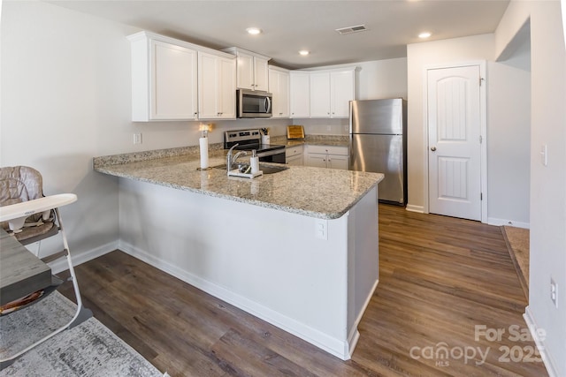 kitchen featuring appliances with stainless steel finishes, dark hardwood / wood-style floors, white cabinets, and kitchen peninsula