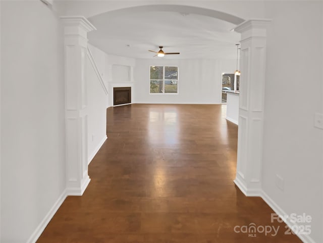 corridor featuring decorative columns and dark wood-type flooring