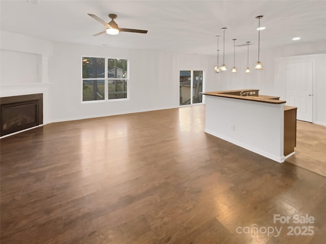 unfurnished living room with dark wood-type flooring and ceiling fan