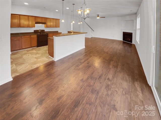 kitchen featuring a kitchen island, ceiling fan with notable chandelier, hanging light fixtures, light hardwood / wood-style floors, and black range with electric stovetop