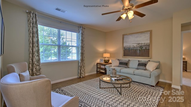 living room featuring visible vents, baseboards, wood finished floors, and a ceiling fan