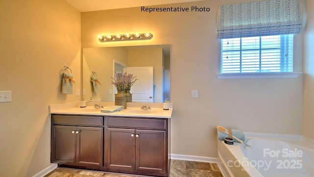 full bathroom featuring double vanity, baseboards, a garden tub, and a sink