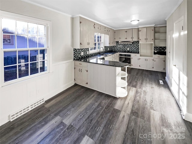 kitchen featuring ornamental molding, kitchen peninsula, sink, and oven