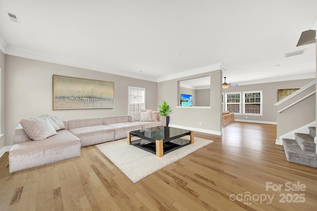 living room with crown molding, light hardwood / wood-style flooring, and ceiling fan