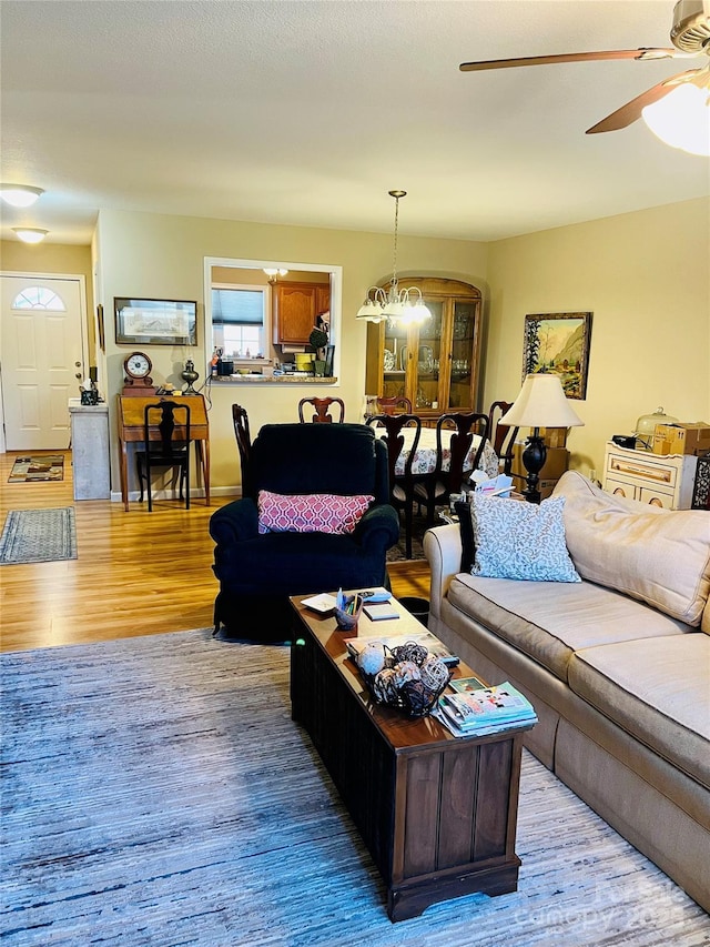 living room with ceiling fan with notable chandelier and light wood-type flooring