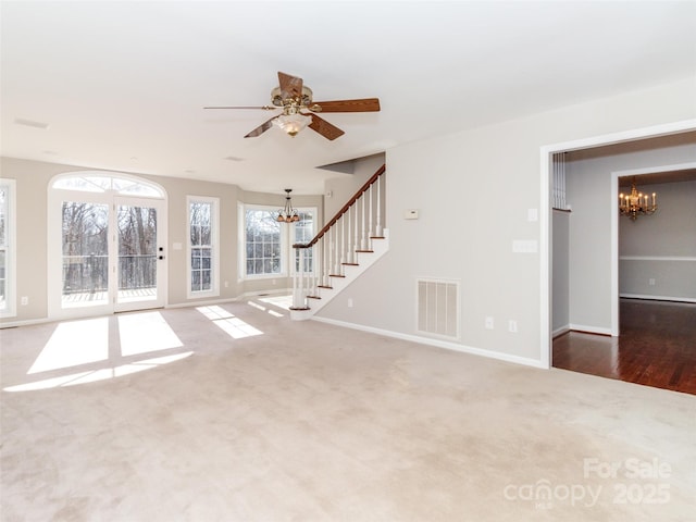 unfurnished living room featuring ceiling fan with notable chandelier and carpet