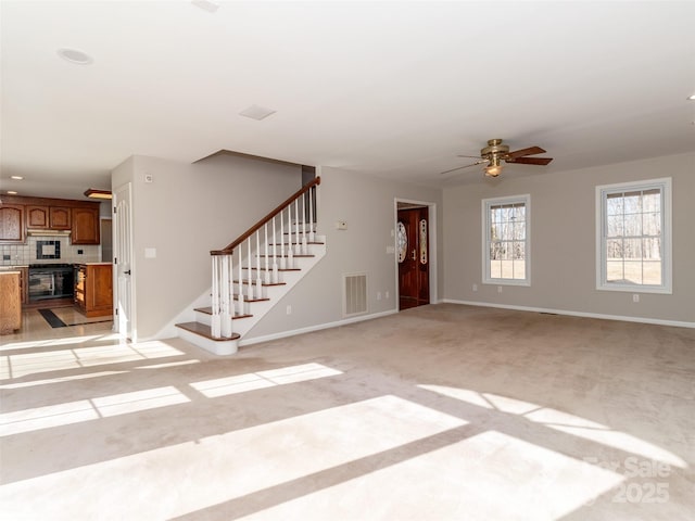 unfurnished living room featuring light colored carpet and ceiling fan