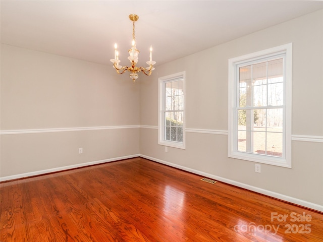 empty room featuring hardwood / wood-style flooring and an inviting chandelier