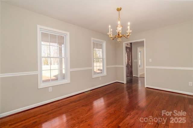 empty room featuring an inviting chandelier and dark wood-type flooring