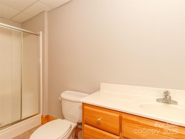 bathroom with a paneled ceiling, tile patterned flooring, vanity, walk in shower, and toilet