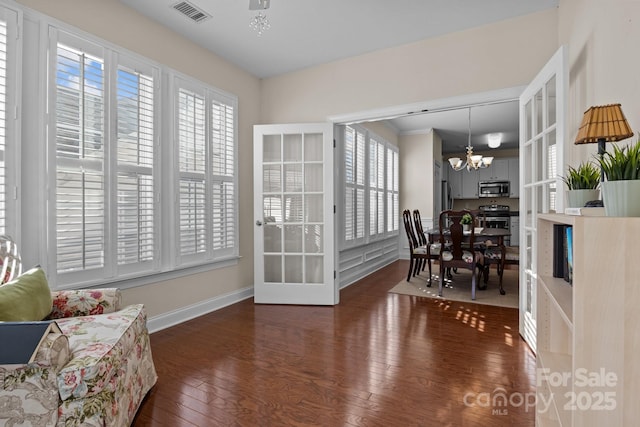 interior space featuring hardwood / wood-style floors, baseboards, visible vents, and a notable chandelier