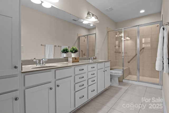 full bath with double vanity, a stall shower, a sink, and tile patterned floors