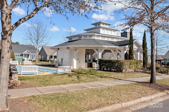 view of front of house with a shingled roof, a front yard, fence, and a chimney