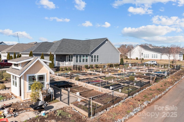 back of house with fence, a vegetable garden, and roof with shingles