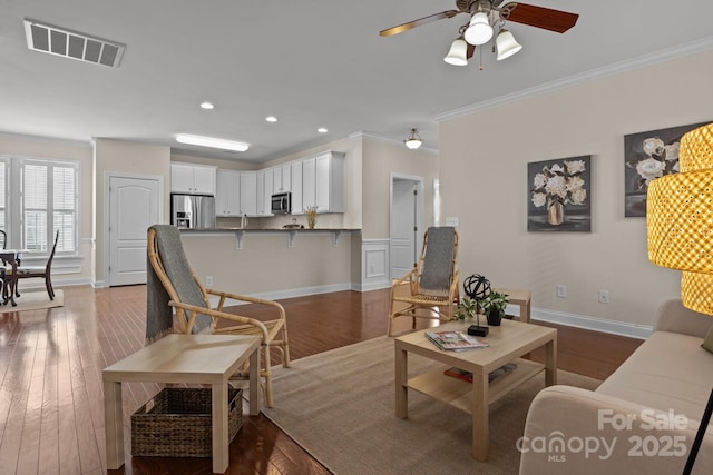 living area featuring recessed lighting, visible vents, crown molding, and wood finished floors