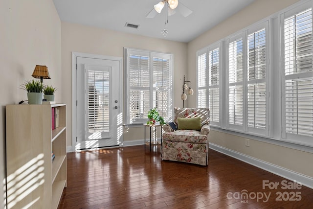 living area with visible vents, a ceiling fan, hardwood / wood-style flooring, and baseboards