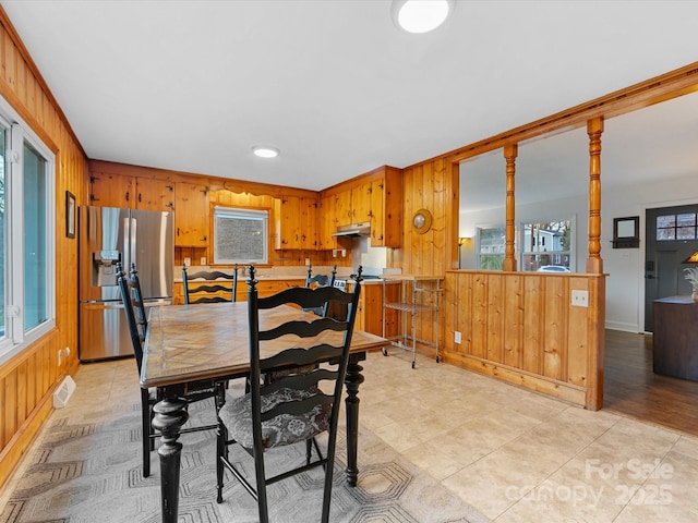 tiled dining space featuring wood walls