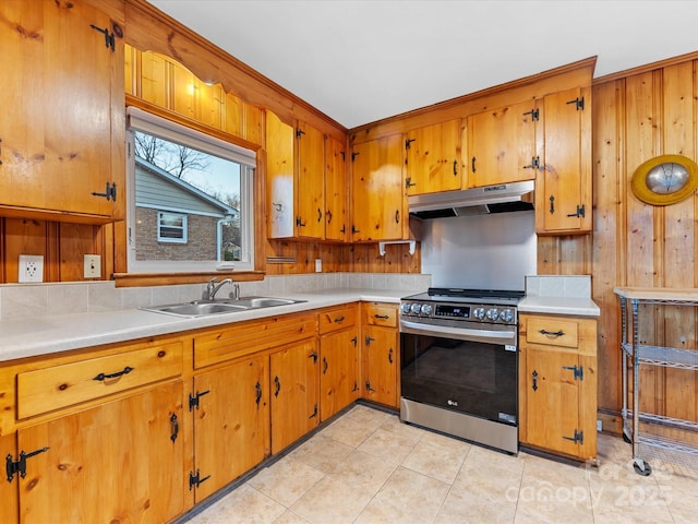 kitchen with stainless steel range with electric stovetop, sink, wooden walls, and light tile patterned flooring