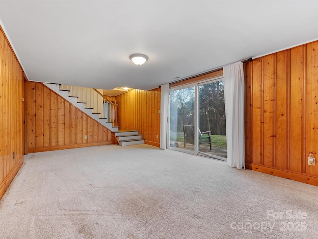 unfurnished living room with wooden walls and light colored carpet