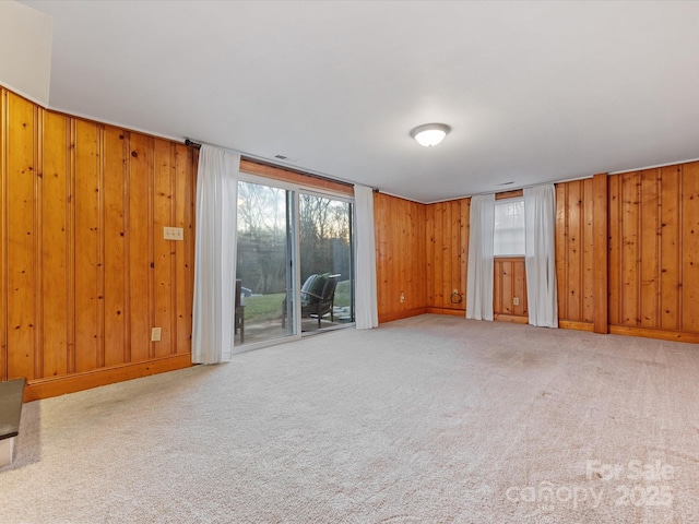 unfurnished living room with wooden walls and light colored carpet