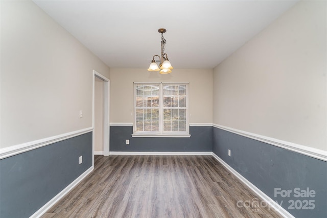 unfurnished dining area featuring an inviting chandelier and dark hardwood / wood-style flooring