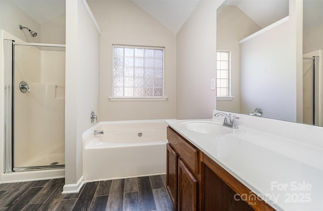 bathroom featuring wood-type flooring, lofted ceiling, vanity, and plus walk in shower