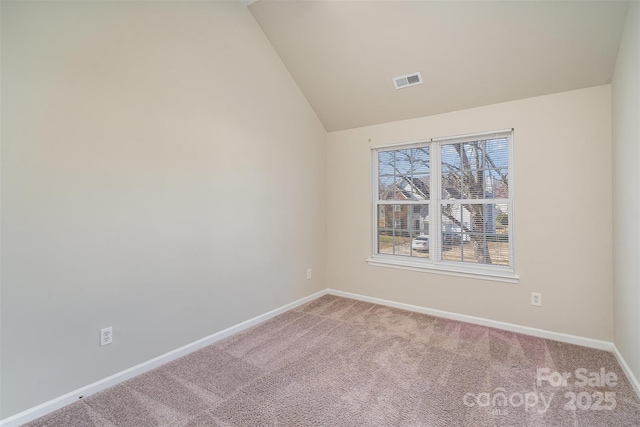 carpeted empty room featuring vaulted ceiling