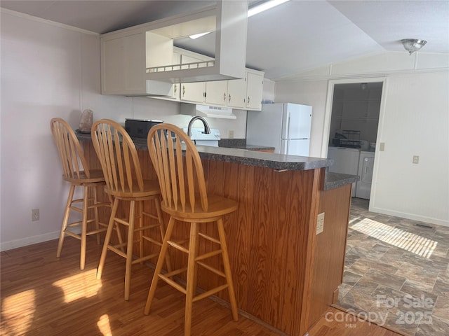 kitchen featuring white cabinets, dark hardwood / wood-style flooring, white fridge, independent washer and dryer, and kitchen peninsula