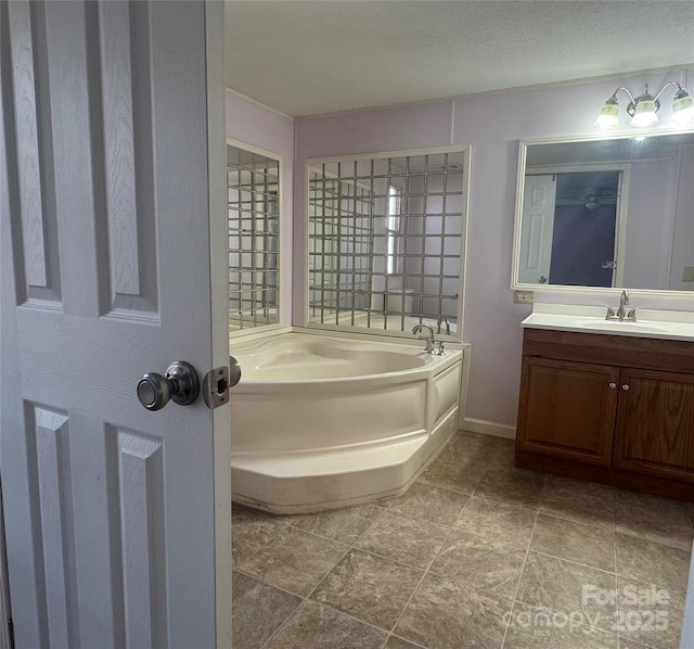 bathroom featuring vanity, a textured ceiling, and a bathing tub