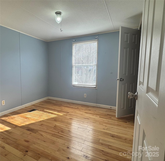 unfurnished room with a textured ceiling and light hardwood / wood-style flooring