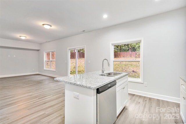 kitchen featuring sink, white cabinets, a kitchen island with sink, stainless steel dishwasher, and light stone counters