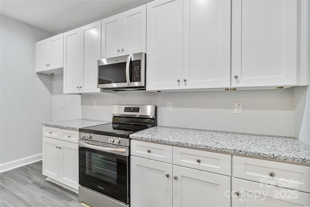 kitchen featuring stainless steel appliances, light stone countertops, light hardwood / wood-style floors, and white cabinets